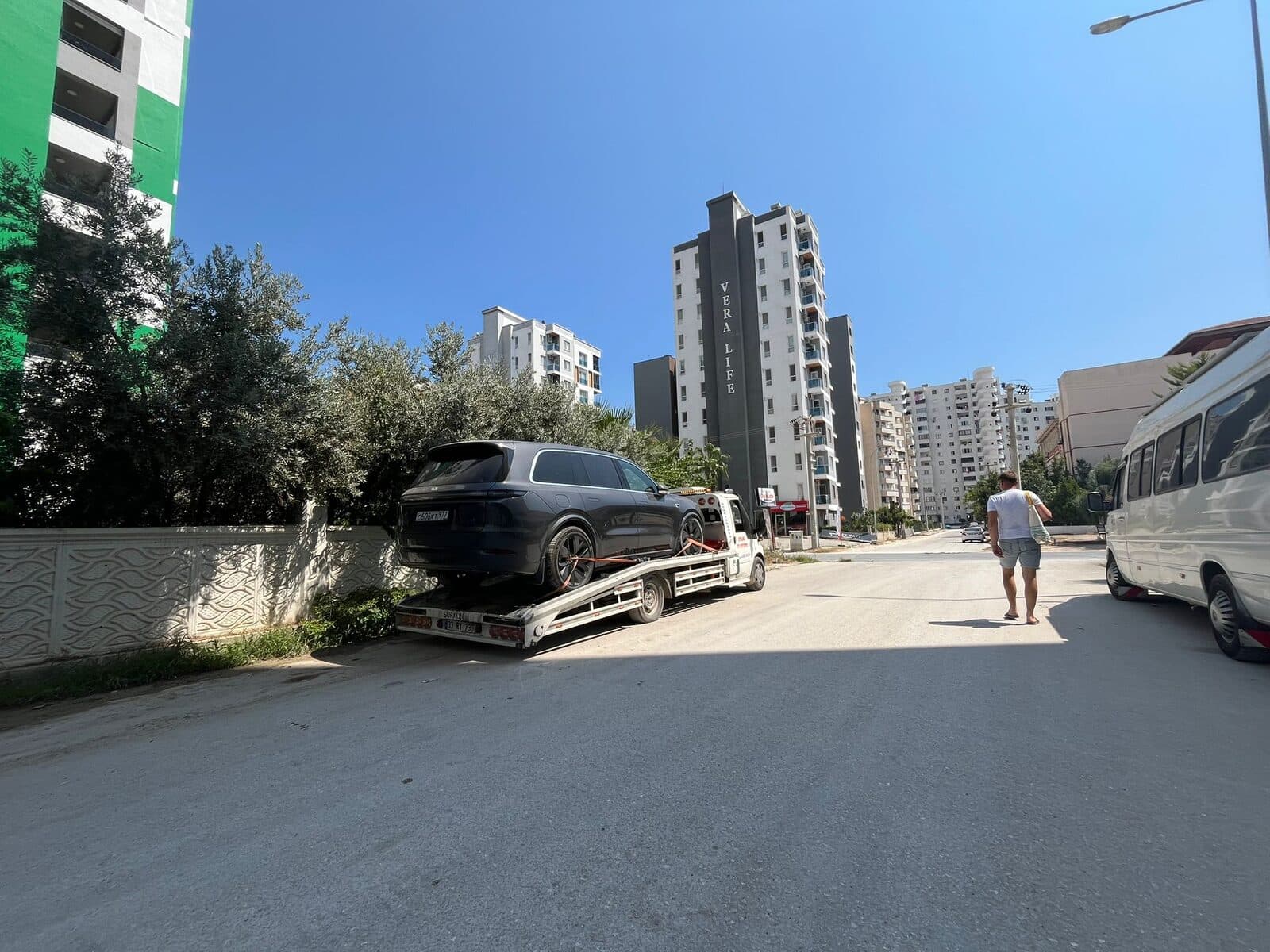 Mahalle içinde araç taşıyan kayar kasa çekicinin uzaktan görünümü